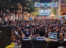 Multitud disfrutando de una verbena con luces y música en la calle.