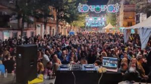 Multitud disfrutando de una verbena con luces y música en la calle.