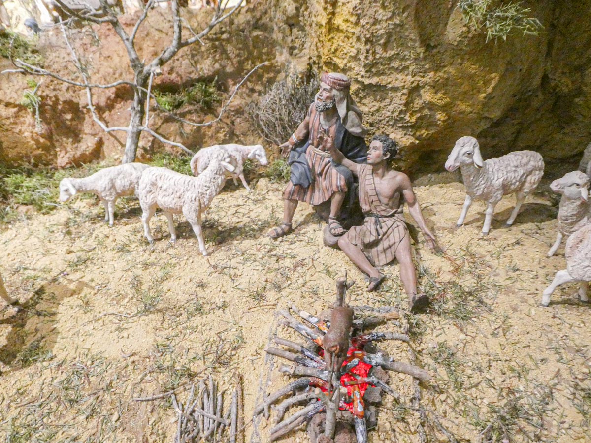 Escena de pastores con ovejas y fuego en el suelo.