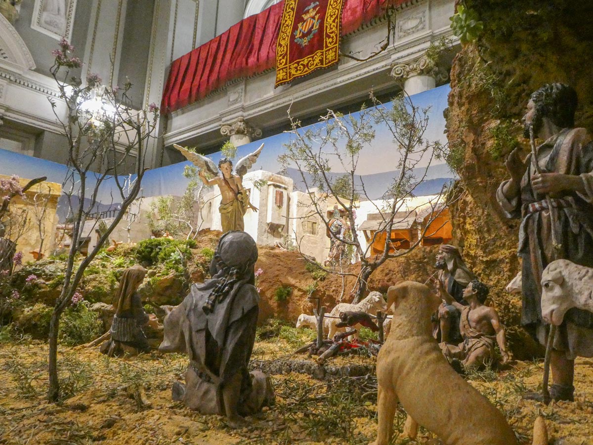 Escena de la natividad con figuras artesanales y un ángel
