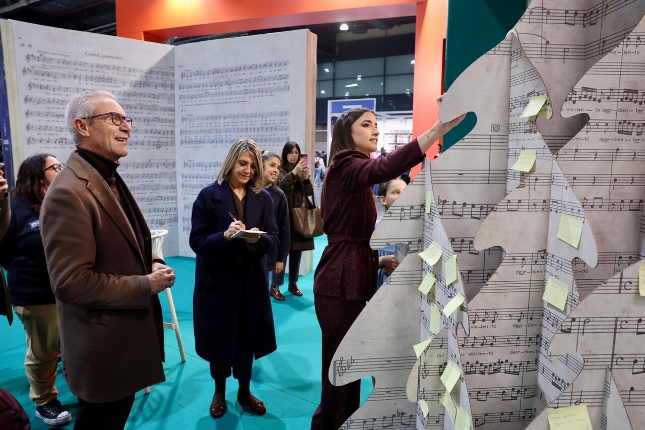 Personas en la inauguración de Expojove 2025 escribiendo en un árbol de notas musicales.