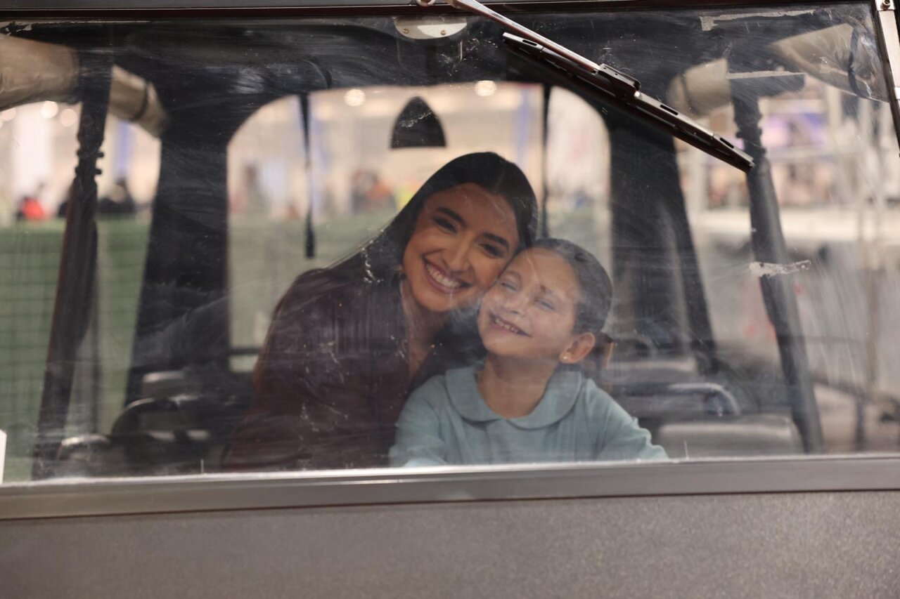 Mujer y niña sonriendo dentro de un vehículo en Expojove 2025