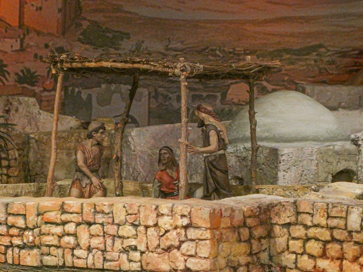 Tres figuras artesanales en un entorno histórico con un pozo.