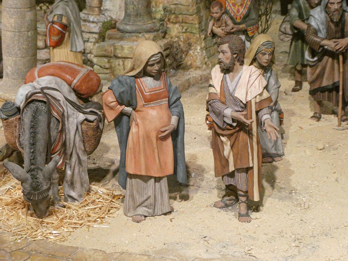 Figuras artesanales de la natividad con un burro en el fondo.