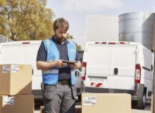 Repartidor con caja y furgonetas de fondo en Valencia