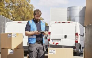 Repartidor con caja y furgonetas de fondo en Valencia