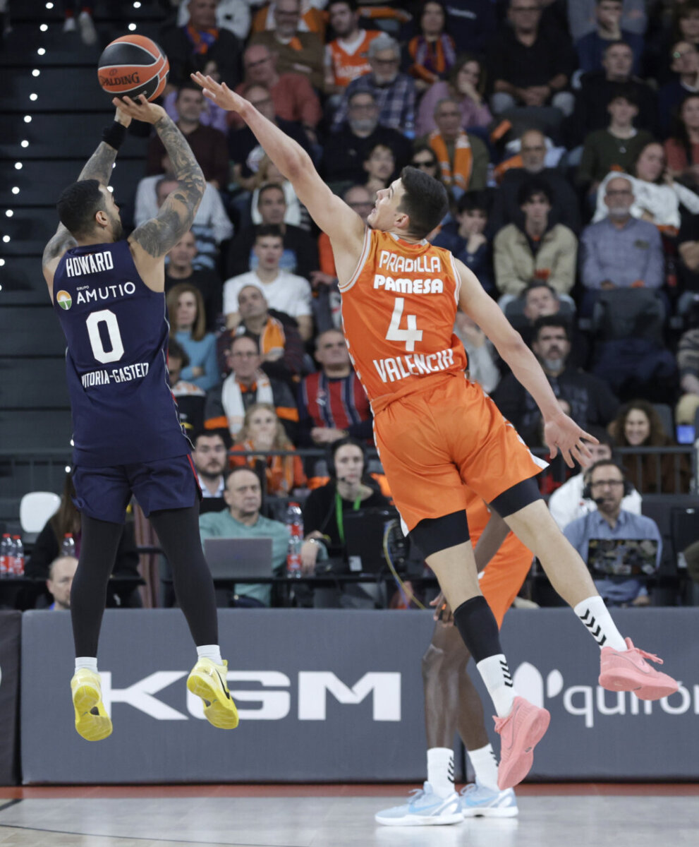 Jugador de Baskonia lanzando a canasta mientras es defendido por un jugador de Valencia Basket.