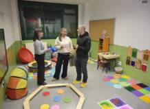 Tres personas conversando en un aula multisensorial colorida.