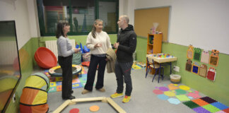 Tres personas conversando en un aula multisensorial colorida.