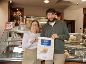 Dos personas sosteniendo un cartel sobre Barberetes en una pastelería