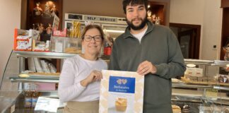 Dos personas sosteniendo un cartel sobre Barberetes en una pastelería