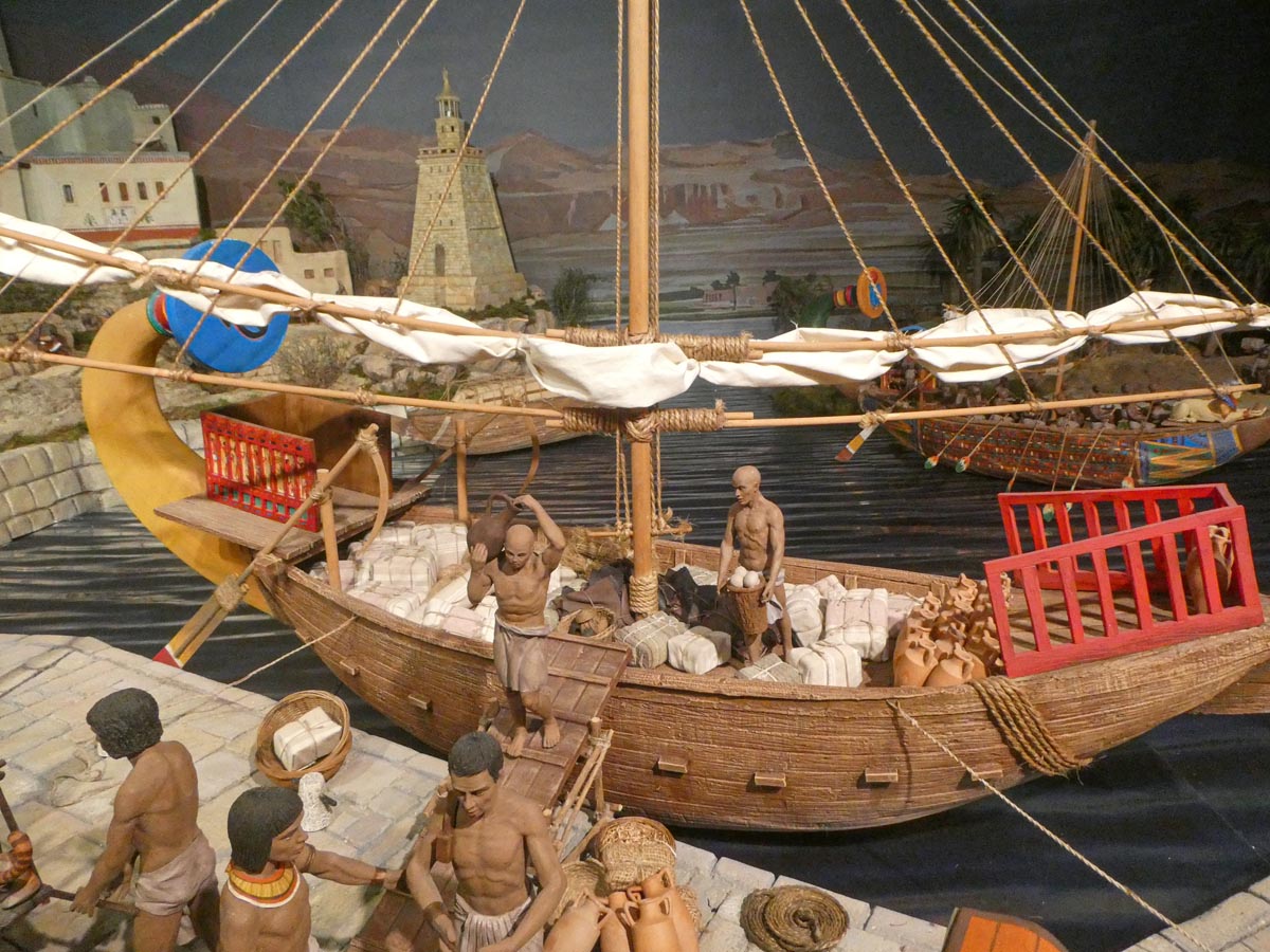 Modelo de barco antiguo con figuras humanas en actividad comercial.