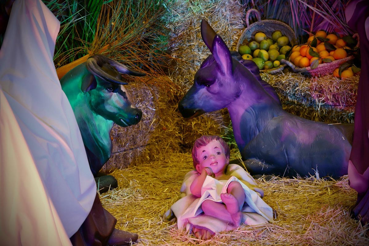 Nacimiento con figuras de animales y un niño en un belén navideño