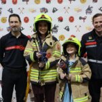 Personas en la inauguración de Expojove 2025 con trajes de bomberos