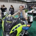 Niña sonriendo mientras monta una moto de la Guardia Civil en Expojove 2025