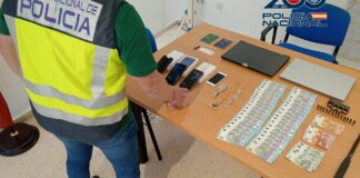 Agente de policía revisando objetos relacionados con una estafa en una mesa