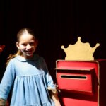 Niña sonriente en un evento con un buzón decorado