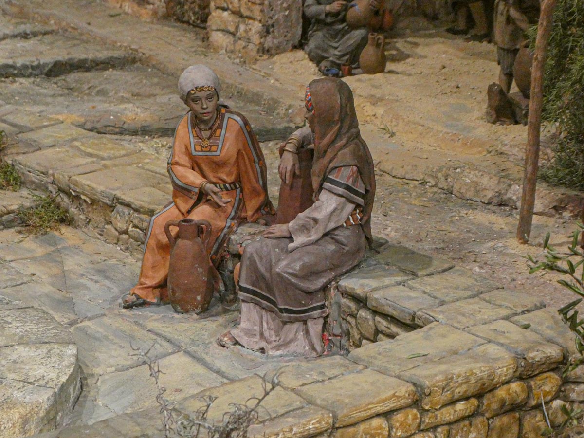 Dos mujeres sentadas conversando en un entorno antiguo.