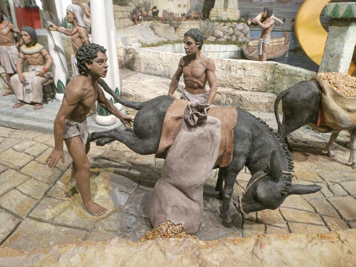 Escena de figuras humanas cargando un asno con sacos.