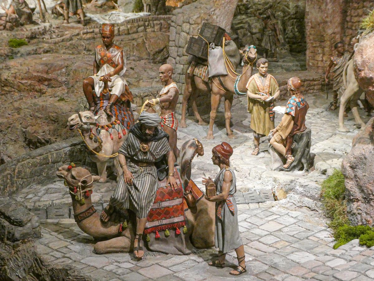 Representación de una escena histórica con camellos y personajes en vestimenta tradicional.