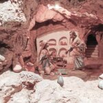 Representación de una escena histórica en una cueva con figuras y utensilios.