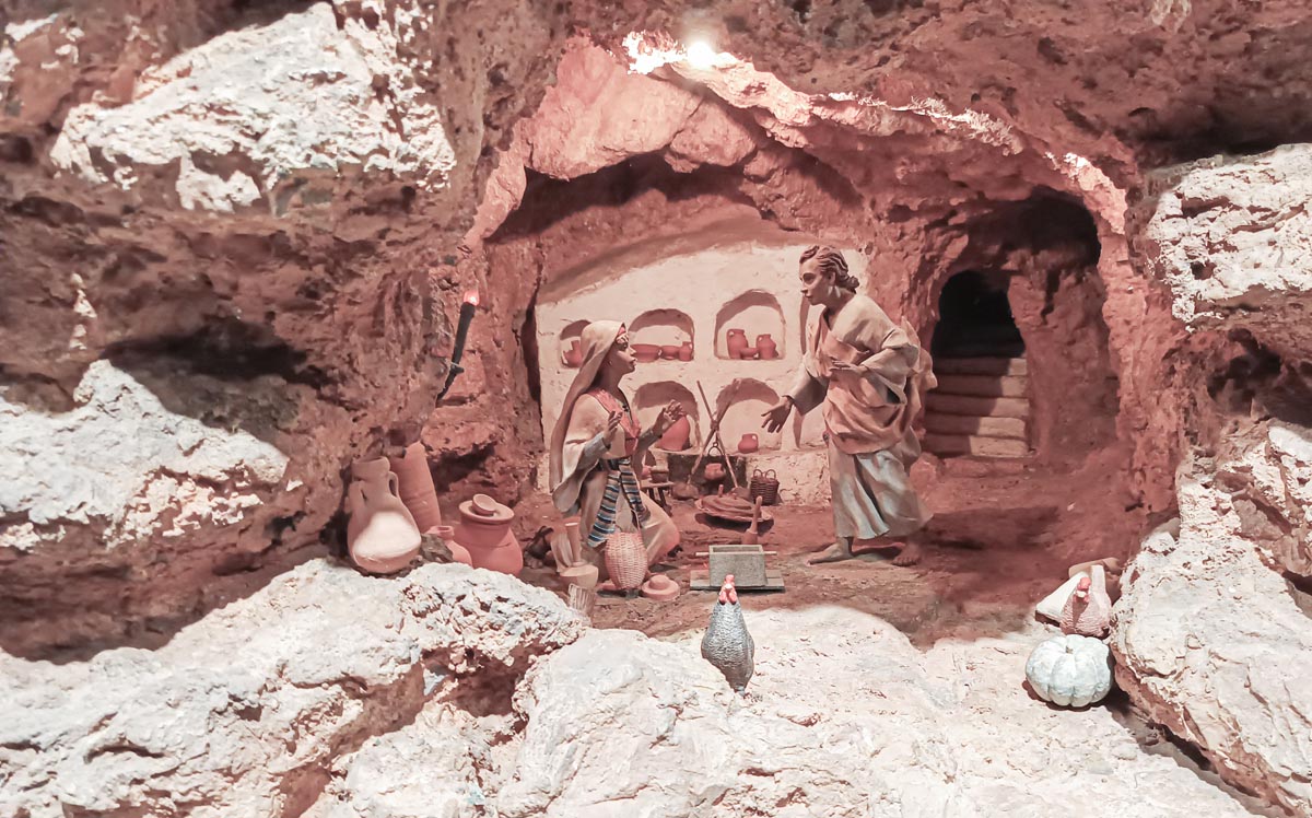 Representación de una escena histórica en una cueva con figuras y utensilios.