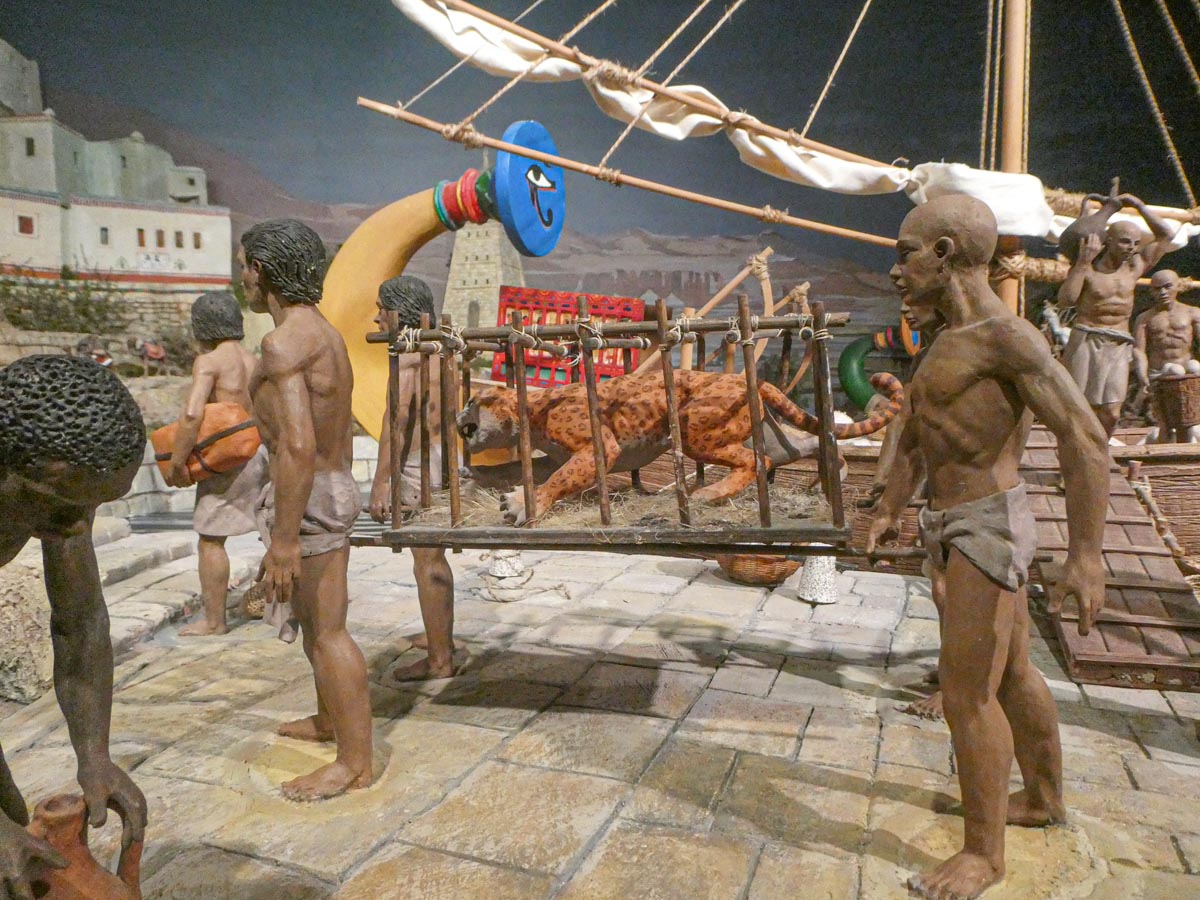 Escena histórica con esculturas de personas cargando un felino