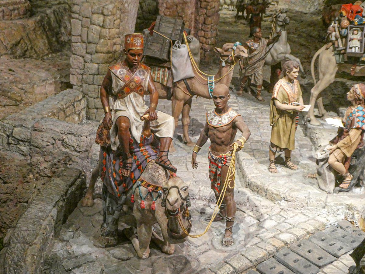 Figuras históricas en una escena con camellos y personas