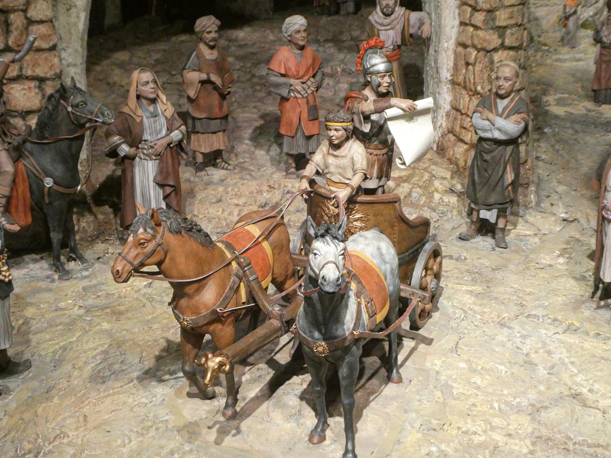 Representación de figuras históricas en un escenario antiguo con caballos y personas.