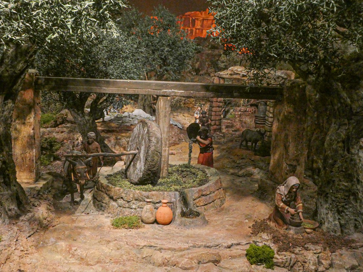 Representación de una escena histórica en un olivar tradicional con figuras humanas.