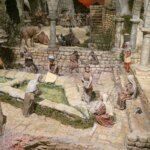 Representación de una escena de un pueblo antiguo con figuras en un entorno rural.