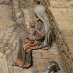 Escena de la natividad con una madre y su hijo en brazos junto a un gato.