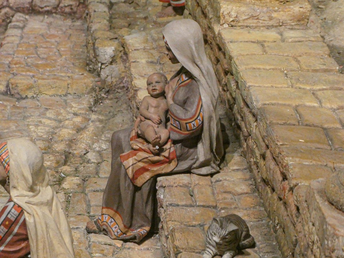 Escena de la natividad con una madre y su hijo en brazos junto a un gato.