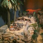 Representación de la natividad con figuras artesanales en un paisaje desértico.