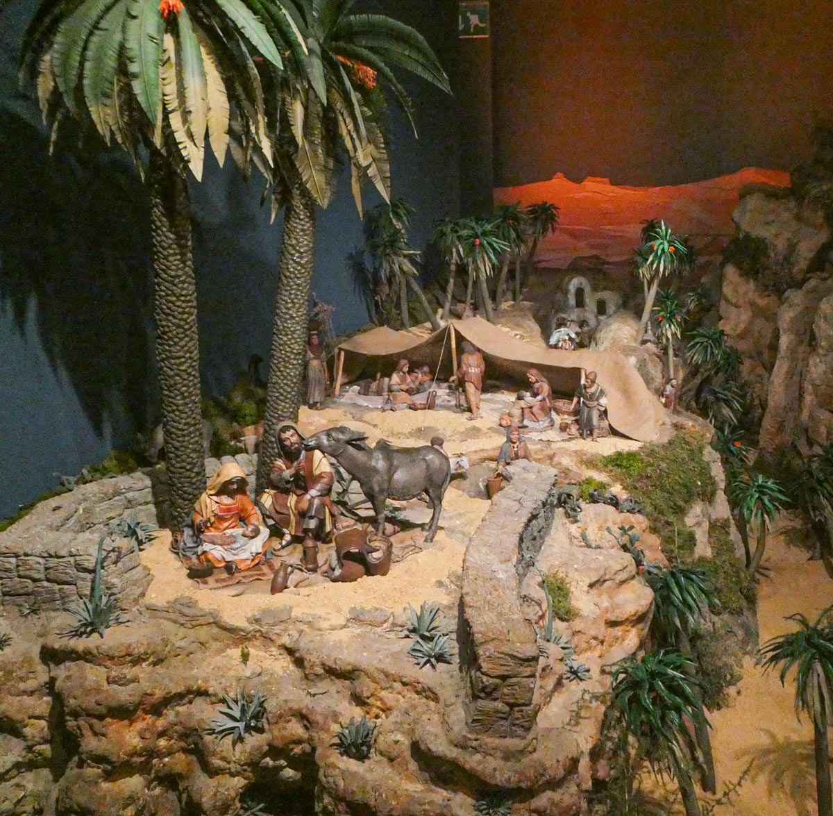Representación de la natividad con figuras artesanales en un paisaje desértico.