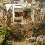 Escena navideña con figuras de pastores y ángeles en un paisaje.