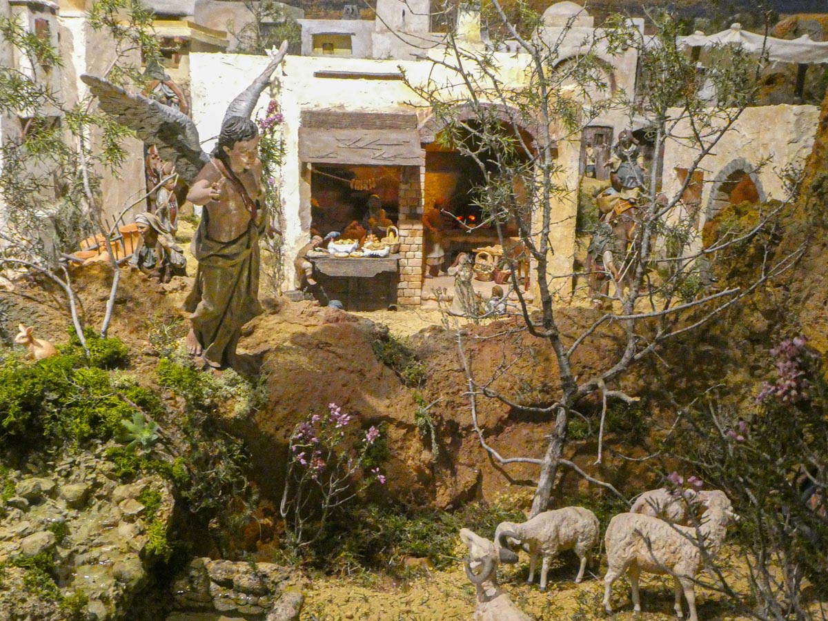 Escena navideña con figuras de pastores y ángeles en un paisaje.