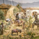 Representación de una escena con personajes y animales en un paisaje árido.