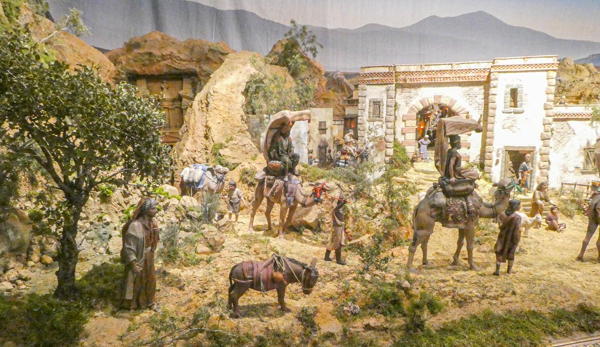 Representación de una escena con personajes y animales en un paisaje árido.