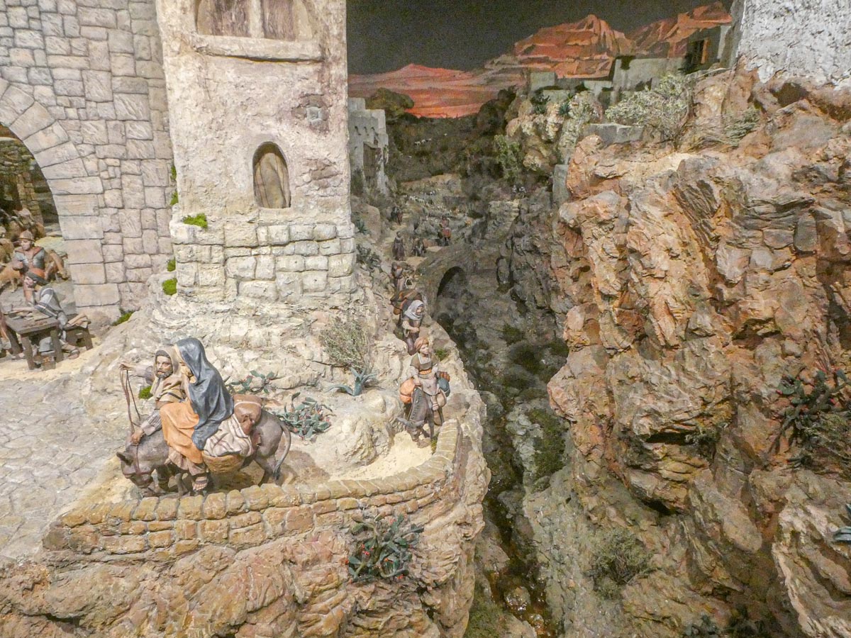 Representación de una escena histórica con figuras en un paisaje rocoso.