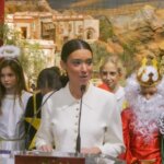 Mujer hablando en un evento navideño con niños disfrazados