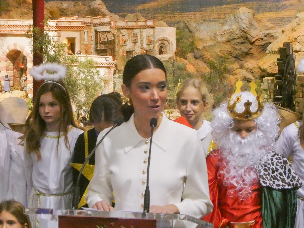 Mujer hablando en un evento navideño con niños disfrazados