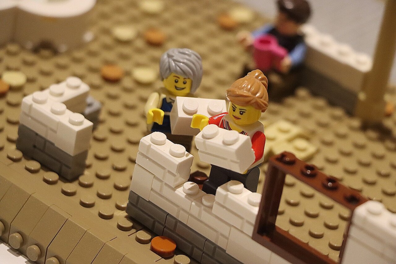 Personas construyendo con bloques de Lego en una exposición.