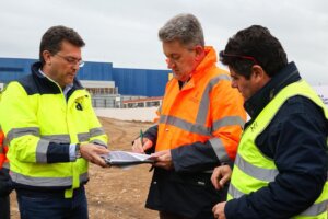 Tres hombres con chalecos reflectantes en un sitio de construcción