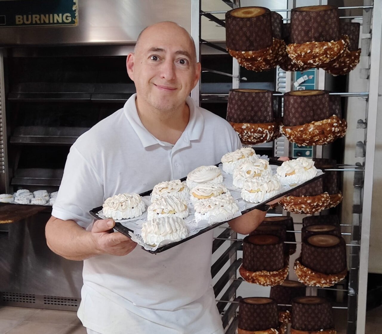 Hombre sosteniendo una bandeja con dulces navideños en una panadería.