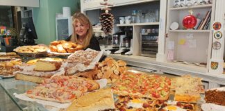Mujer sonriente en una panadería con productos navideños variados.