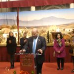 Inauguración de un belén navideño con varias personas en el escenario.