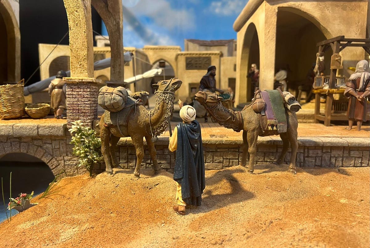 Escena de un belén con camellos y figuras en un mercado