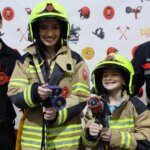 Personas en la inauguración de Expojove 2025 con trajes de bomberos