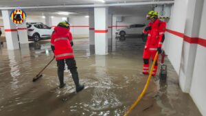 Bomberos trabajando en un garaje inundado por la intensa lluvia en la Horta Sud